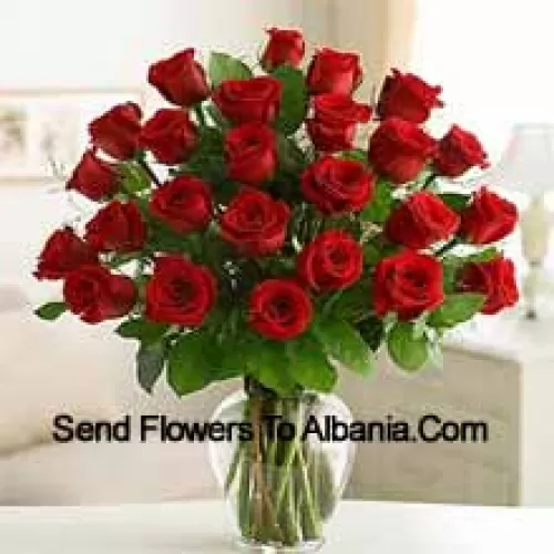 25 roses rouges avec quelques fougères dans un vase en verre